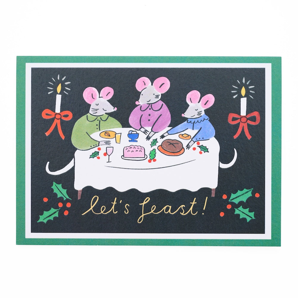Card with illustration of three mice at a table with food, candles, and holly leaves on a black background with the text 'let's feast'.
