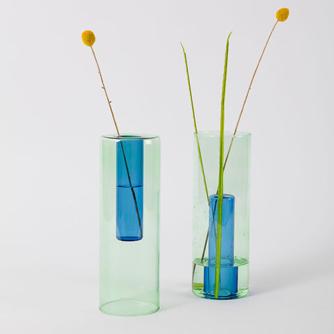 Reversible glass vase in green and blue styled with an orange flower.