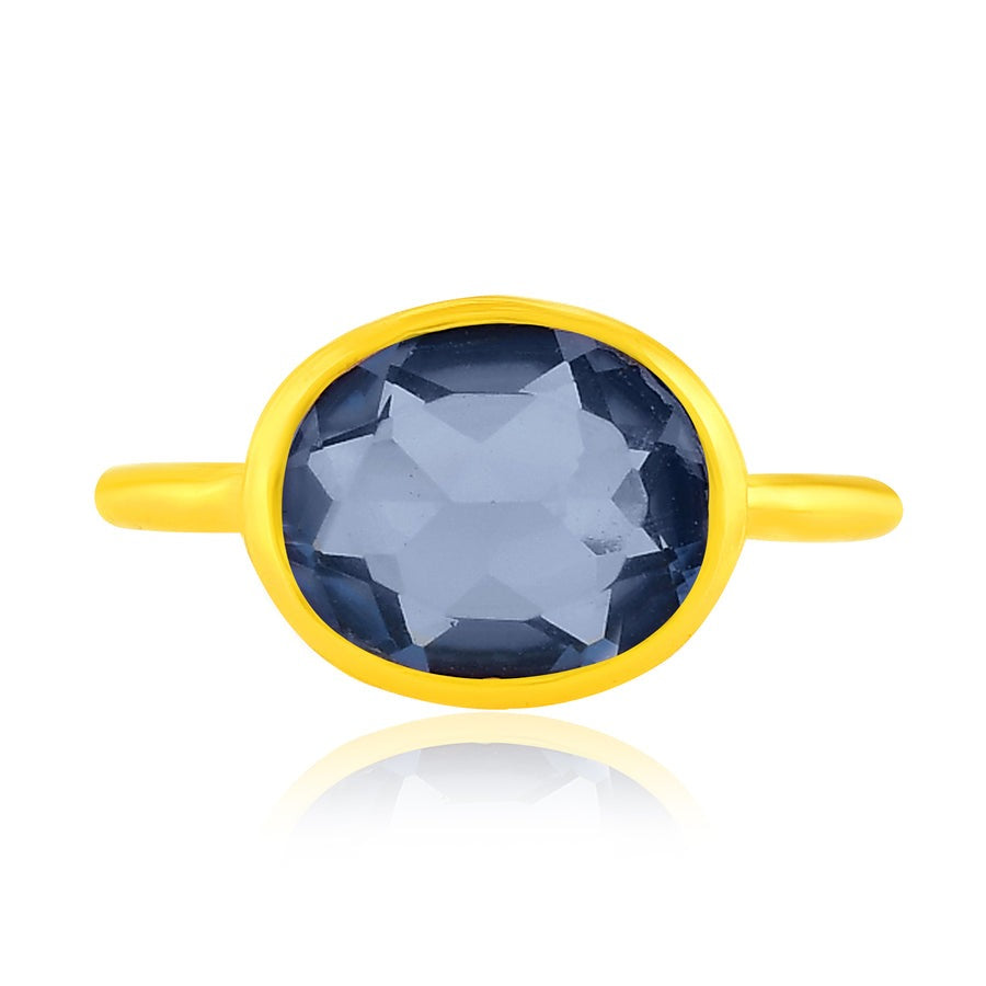 Top view of a gold band ring with large blue crystal in the centre.