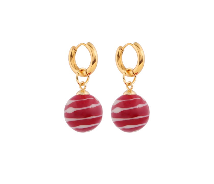 A pair of gold plated hoops each holding a red and white ball shaped pendant.
