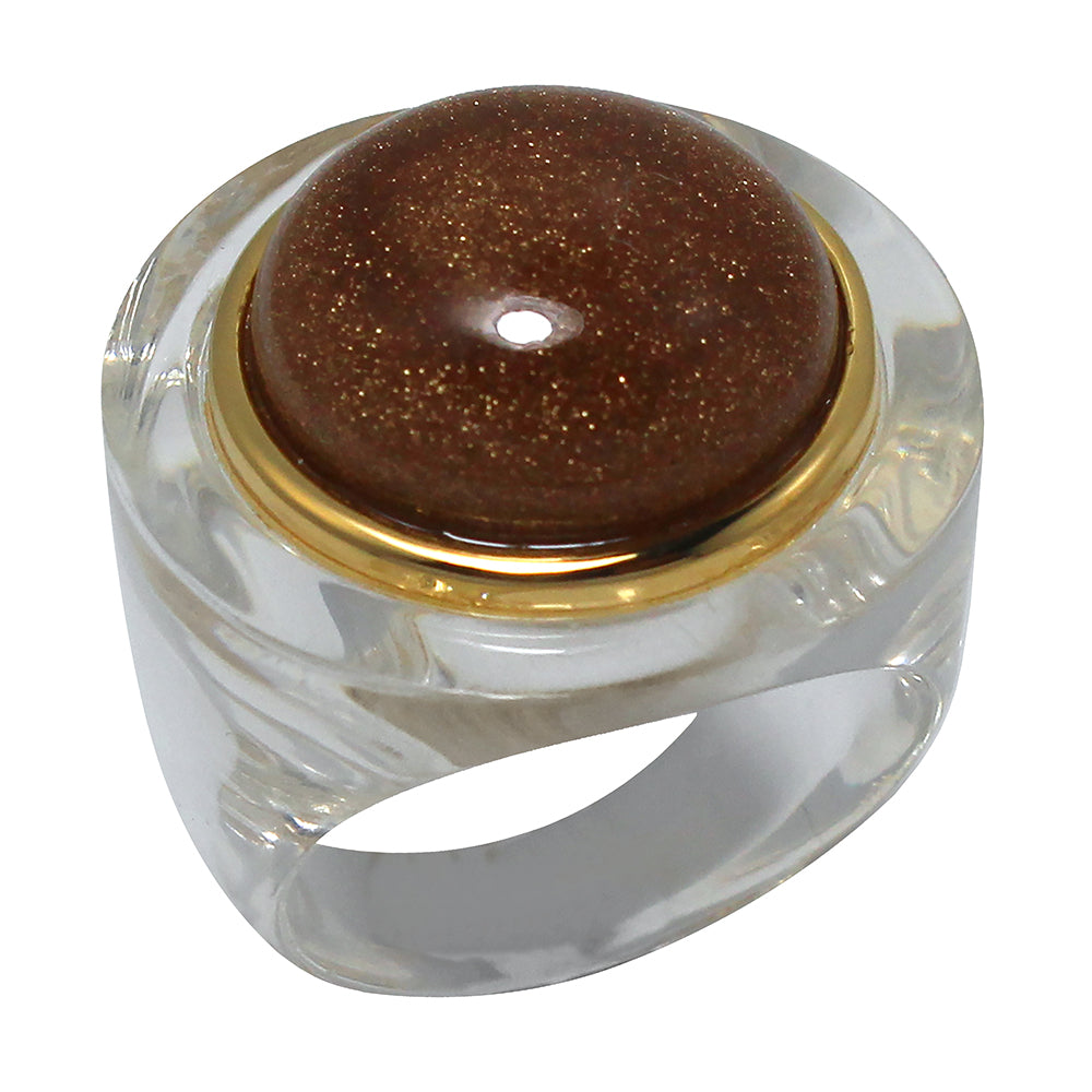 A chunky clear resin ring with a central round charm in glittering sandstone and an outer ring of gold.