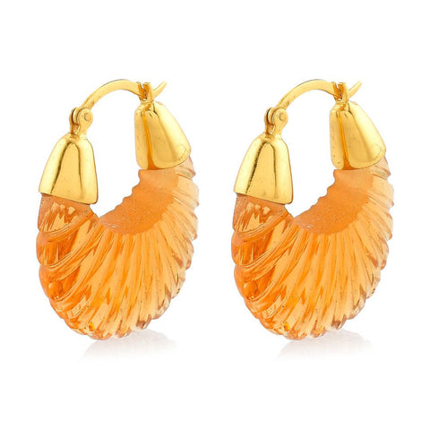 A pair of cut glass pendants in champagne colour hanging from gold hoop earrings.