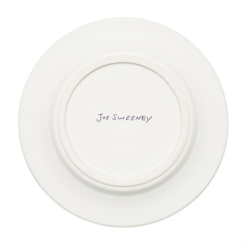 A white ceramic plate shown from the back, featuring a circular raised rim and the name 'joe sweeney' written in black ink at the center.