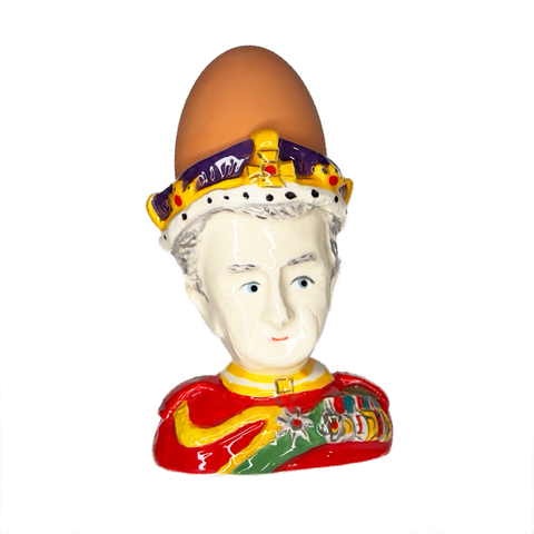 King Charles III ceramic egg cup bust with red uniform and crown, front view with a boiled egg in it.