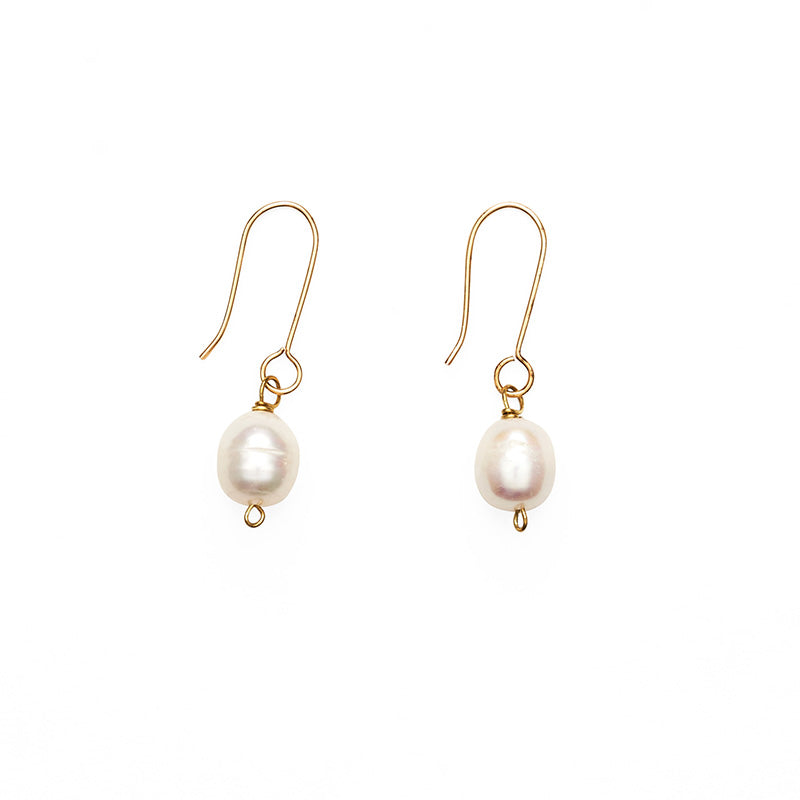A pair of earrings featuring a single pearl hanging from a gold hook.