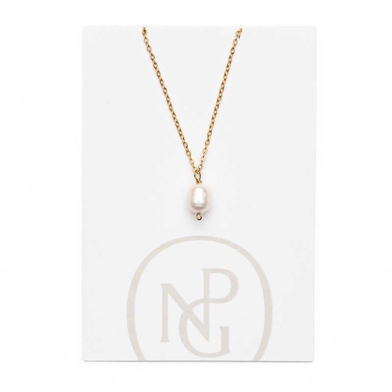 Large single pearl pendant handing from a gold chain necklace attached to npg packaging.