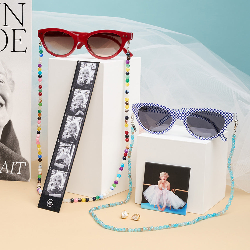 Two pairs of sunglasses, photographic bookmark and magnet of a woman in a tutu against a blue and beige background.