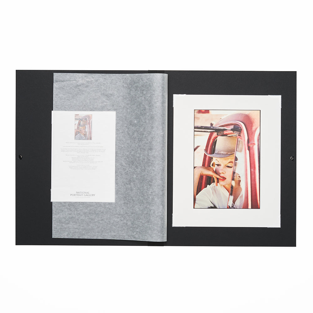 Open folio with a black cover displaying a photo of a woman in a car and a certificate of authenticity.