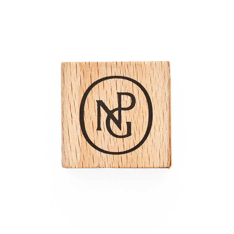 A square wooden sharpener with the npg monogram in black on top.