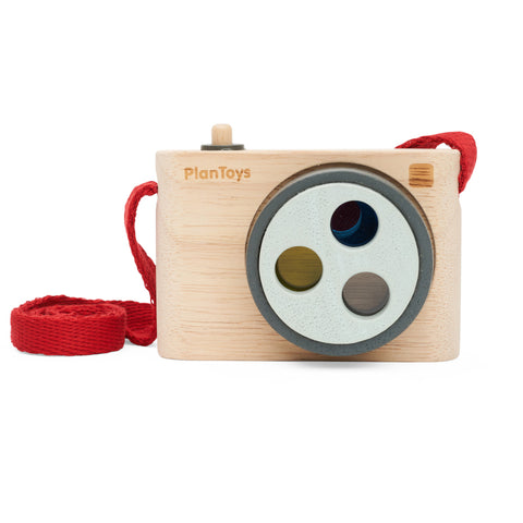 Wooden camera with rotating lenses in multiple colours and a red carry strap..