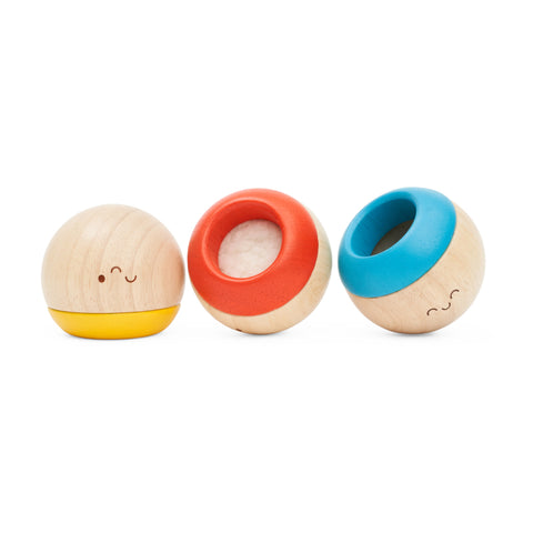 Three round wooden sensory tumbling toys with smiling faces upside down and on their side.