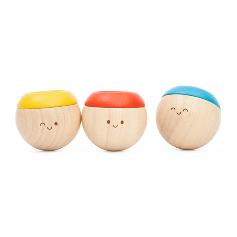 Three round wooden sensory tumbling toys with smiling faces standing in a row.