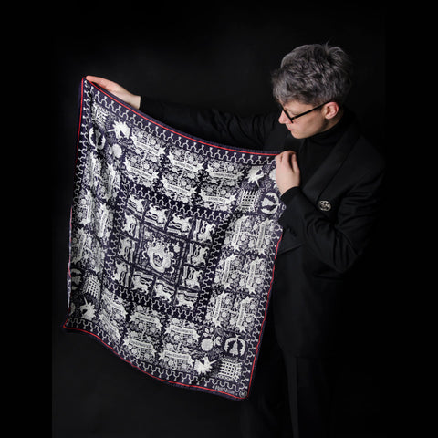 King Charles III Coronation design silk pocket square scarf by Rory Hutton in neutral and black colourway being held up by artist.