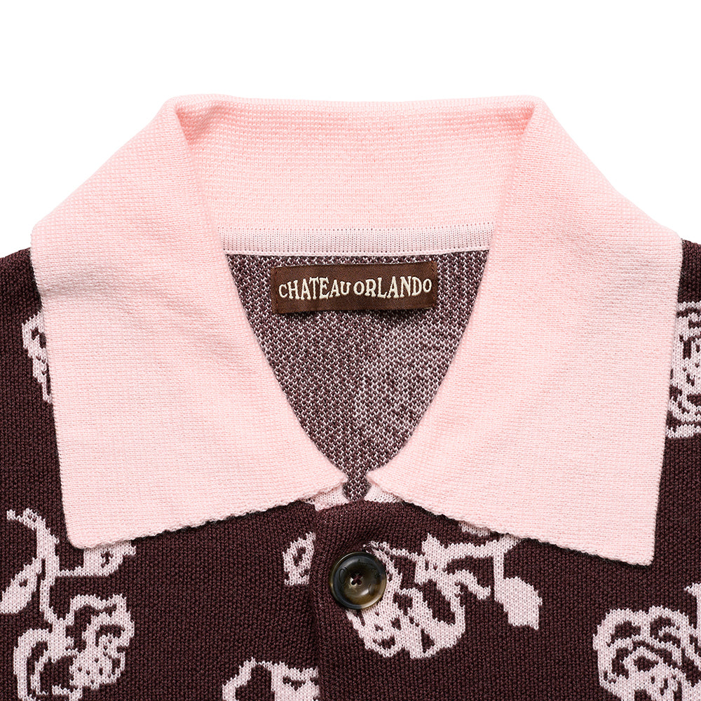 Close up of a brown cardigan with a pink collar and brand label on a white background