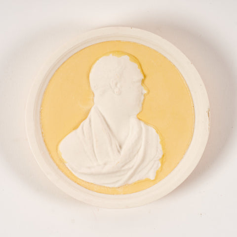 A round plaque in yellow and white featuring a raised side profile portrait of Sir Walter Scott.