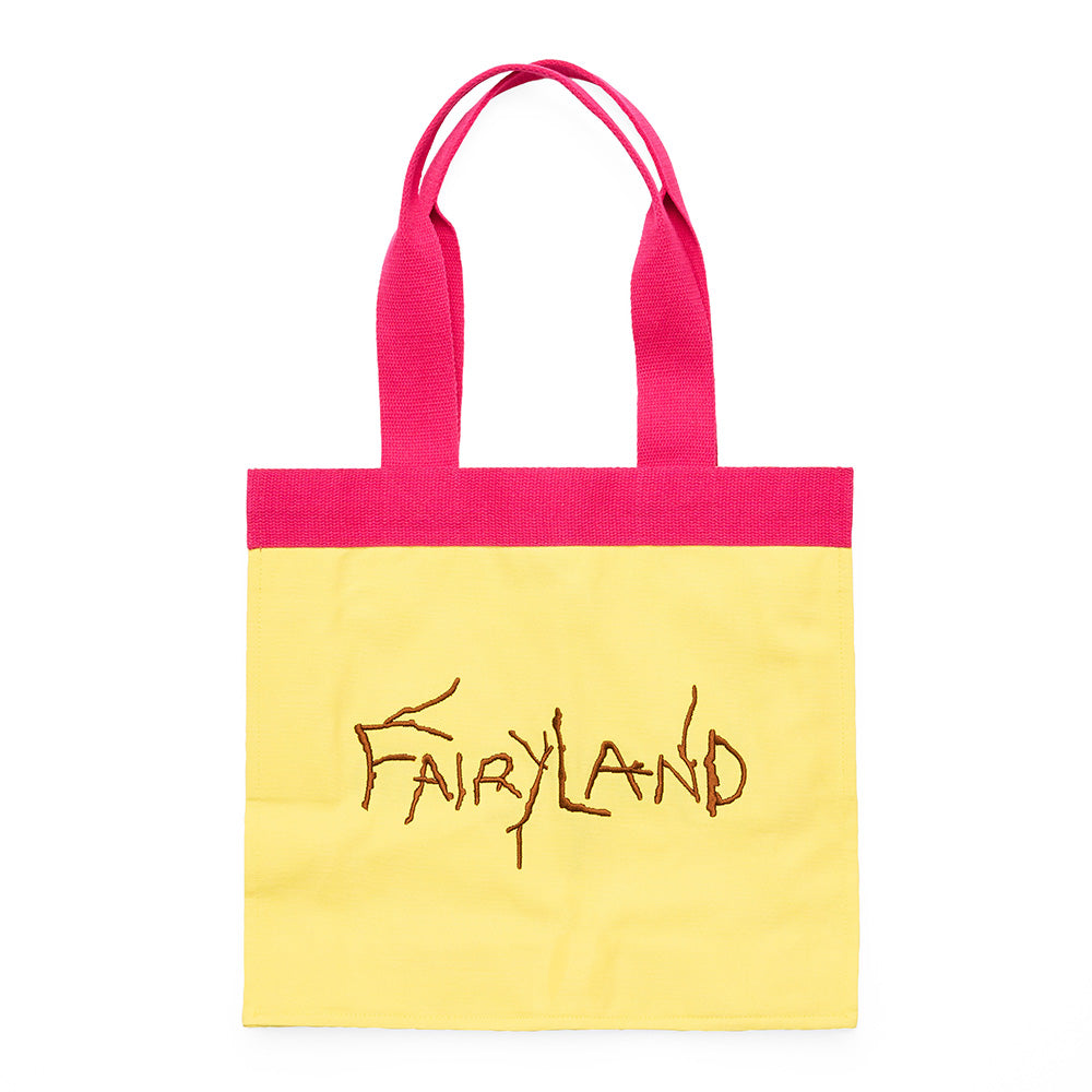 A yellow canvas tote bag with a hot pink top border and matching pink handles, featuring the word 'fairyland' embroidered in brown across the front.