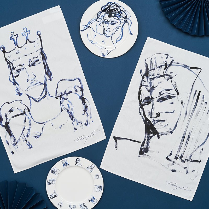 Artistic tea towels and plates with abstract face designs on a blue background.