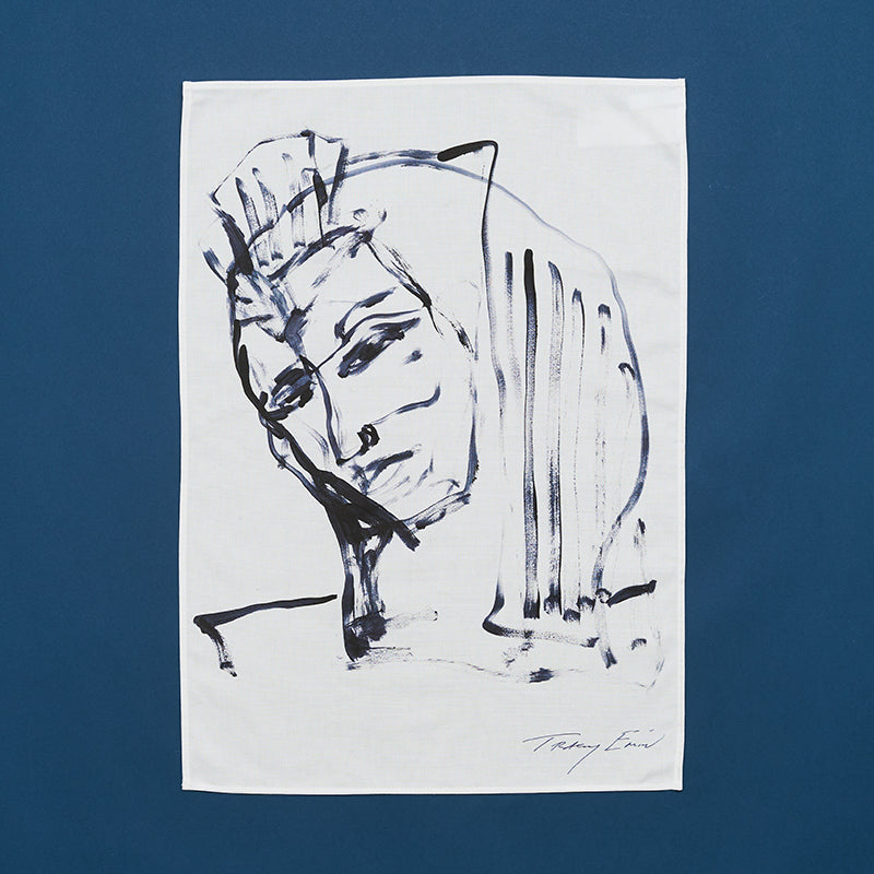 A white cotton tea towel with a blue portrait drawing printed on it, signed by tracey emin at the bottom.