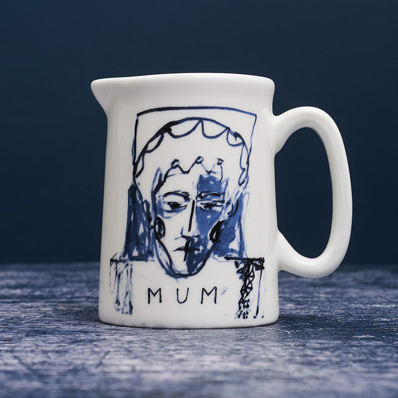 White ceramic milk jug with blue ink portrait painting of a woman with the word 'mum' below.
