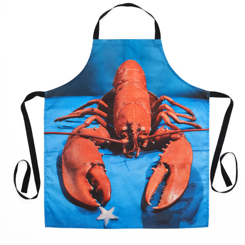 Kitchen apron with photographic print featuring a red lobster holding a silver star against blue background with black neck strap and ties, by Yevonde.