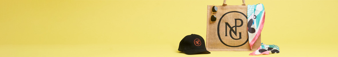 A t shirt with the words 'portraits to dream in' styled with a tote bag and exhibition book.