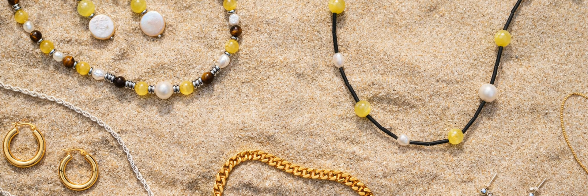 A selection of beaded and chain necklaces on sand