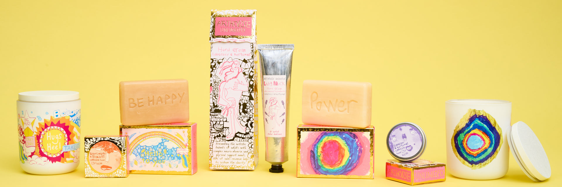 A selection of soaps, candles and hand creams displayed in a row against a yellow background.