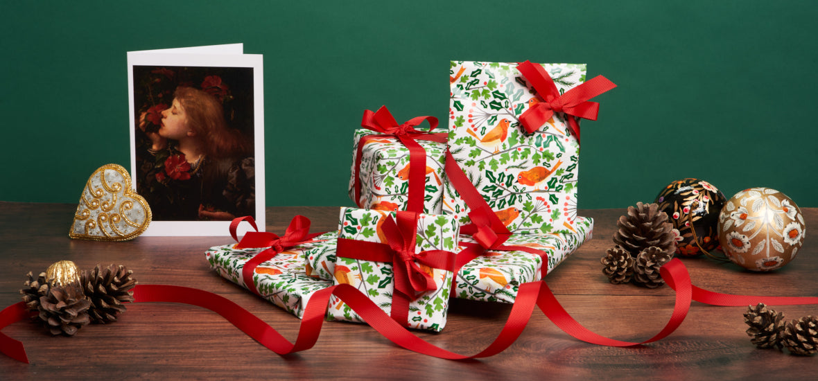 Wrapped christmas gifts in robin paper with red ribbon and greetings card.