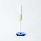 Tall glass candlestick holder in green, pink and blue colour block sections.
