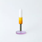 Glass candlestick holder in orange, grey and purple block colour sections.