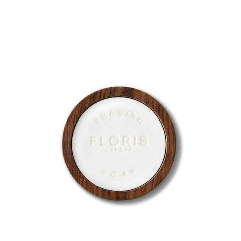 Round white soap carved with 'Floris' in a round wooden bowl.