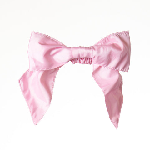 A scrunchie hair accessory featuring a bow made from pink satin