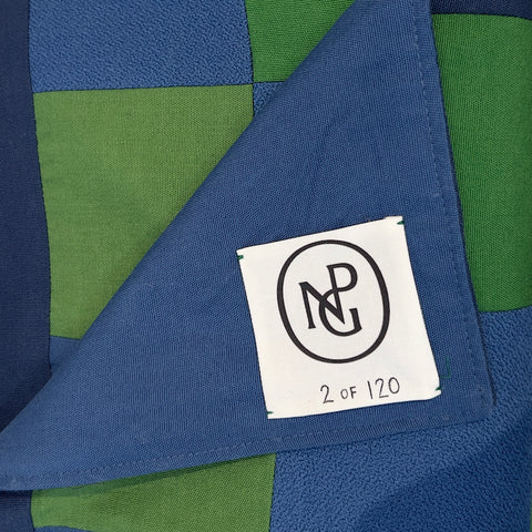 Detail of the NPG logo on the green and blue chequered throw blanket.