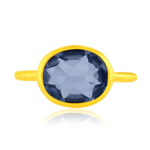 Top view of a gold band ring with large blue crystal in the centre. 