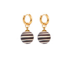 A pair of gold plated hoops each holding a black and white ball shaped pendant. 
