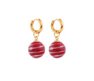 A pair of gold plated hoops each holding a red and white ball shaped pendant. 