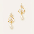 A pair of gold dangle earrings with clear crystal clusters at the top and a teardrop-shaped white pearl hanging below, set against a plain off-white background.