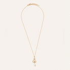 A delicate gold chain necklace with a small heart-shaped pendant set with tiny clear stones and a dangling white pearl, displayed on a clean off-white background.