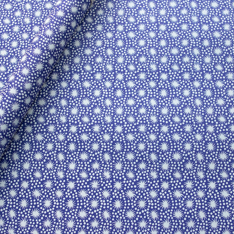 Blue wrapping paper with white dots and swirly stars printed on it. 