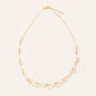 A delicate gold chain necklace adorned with pearls arranged in a curved, tiered design, displayed on a clean off-white background.