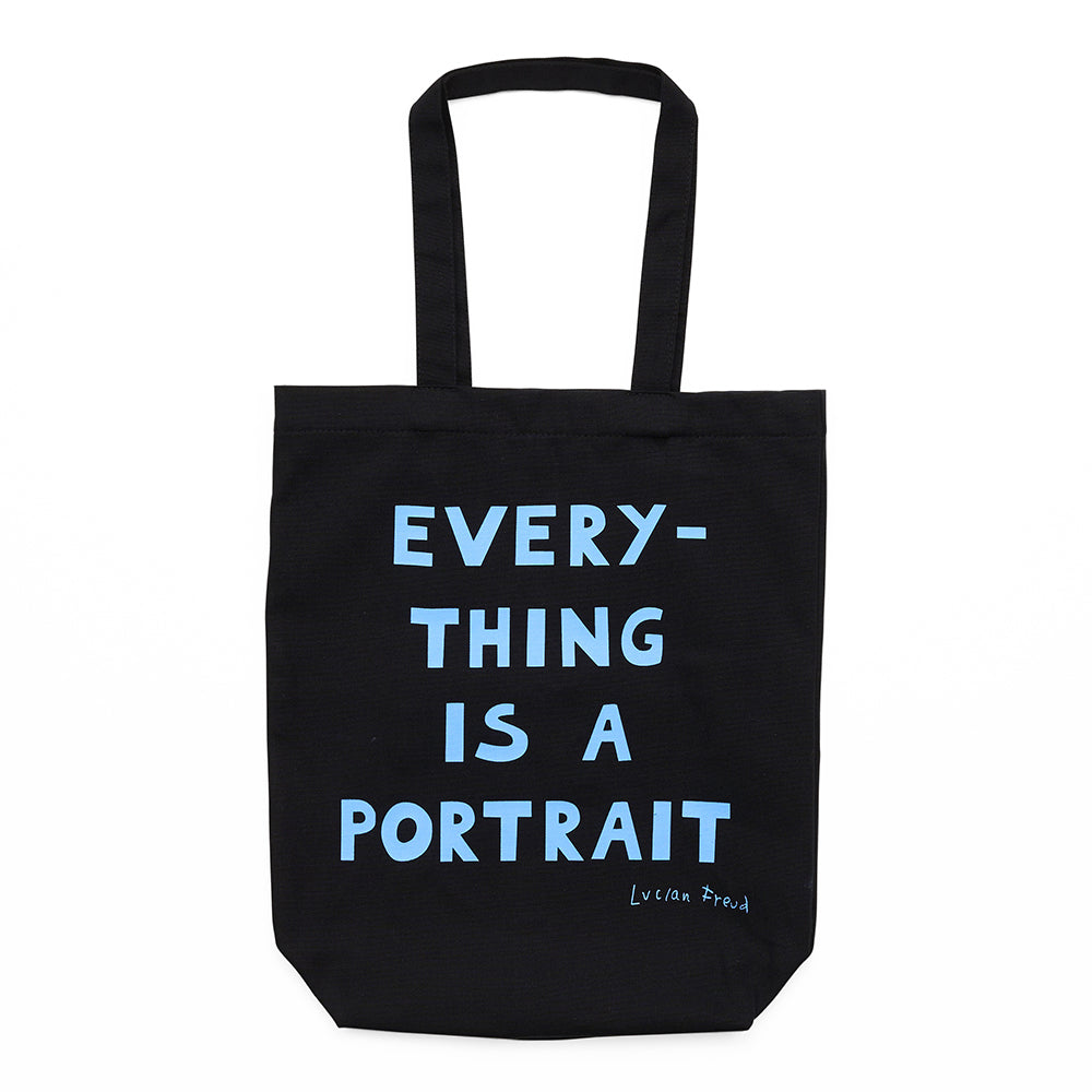 Black tote bag with handles and the words 'everything is a portrait, lucian freud' in blue text. 
