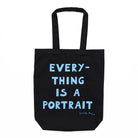 Black tote bag with handles and the words 'Everything is a Portrait, Lucian Freud' in blue text. 