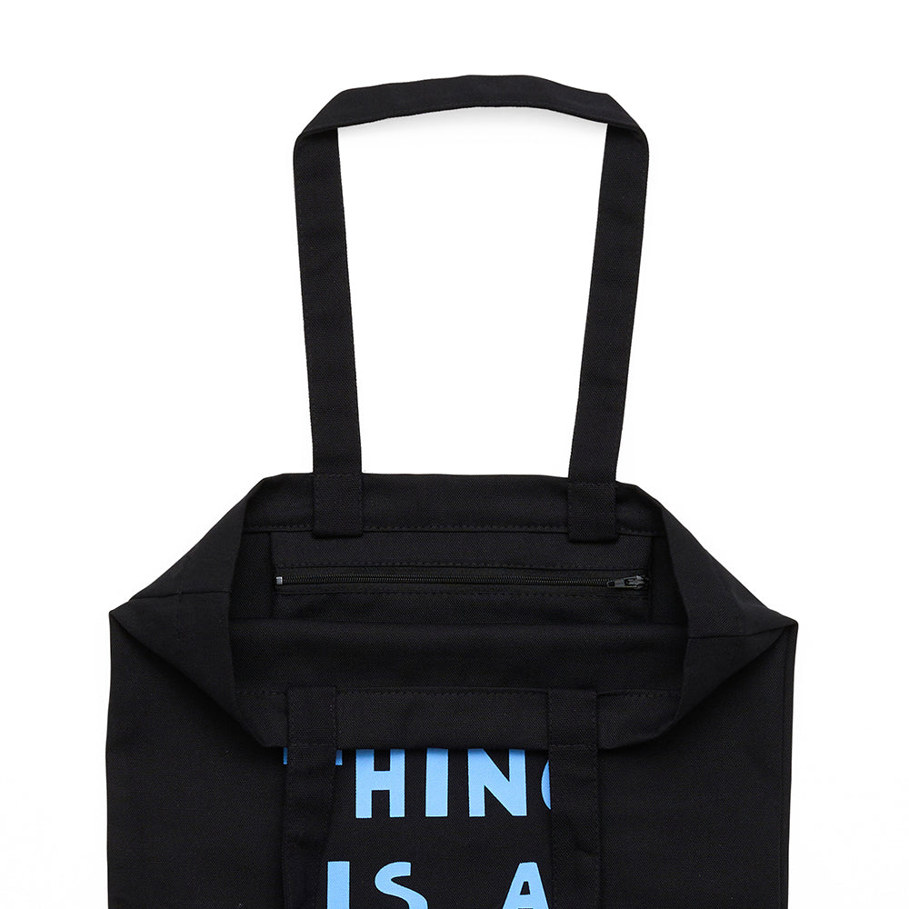 Interior view of a zipped pocket inside of a black tote bag with handle. 