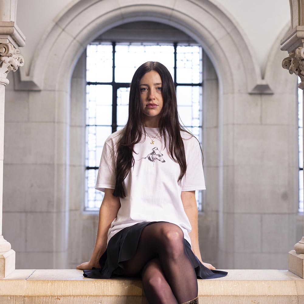 Woman sitting on a ledge in an architectural setting wearing a dog design t shirt