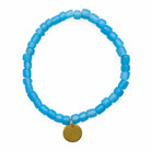 Blue beaded bracelet with a circular brass charm on a white background
