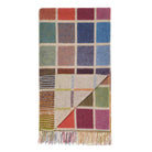A wool blanket with blocks of colour and tassels at the edges against a white background.