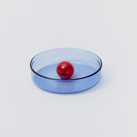 Round blue glass dish with central red bubble.