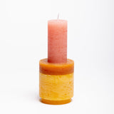 Three-tiered stackable candles in the colours red, orange and yellow. 