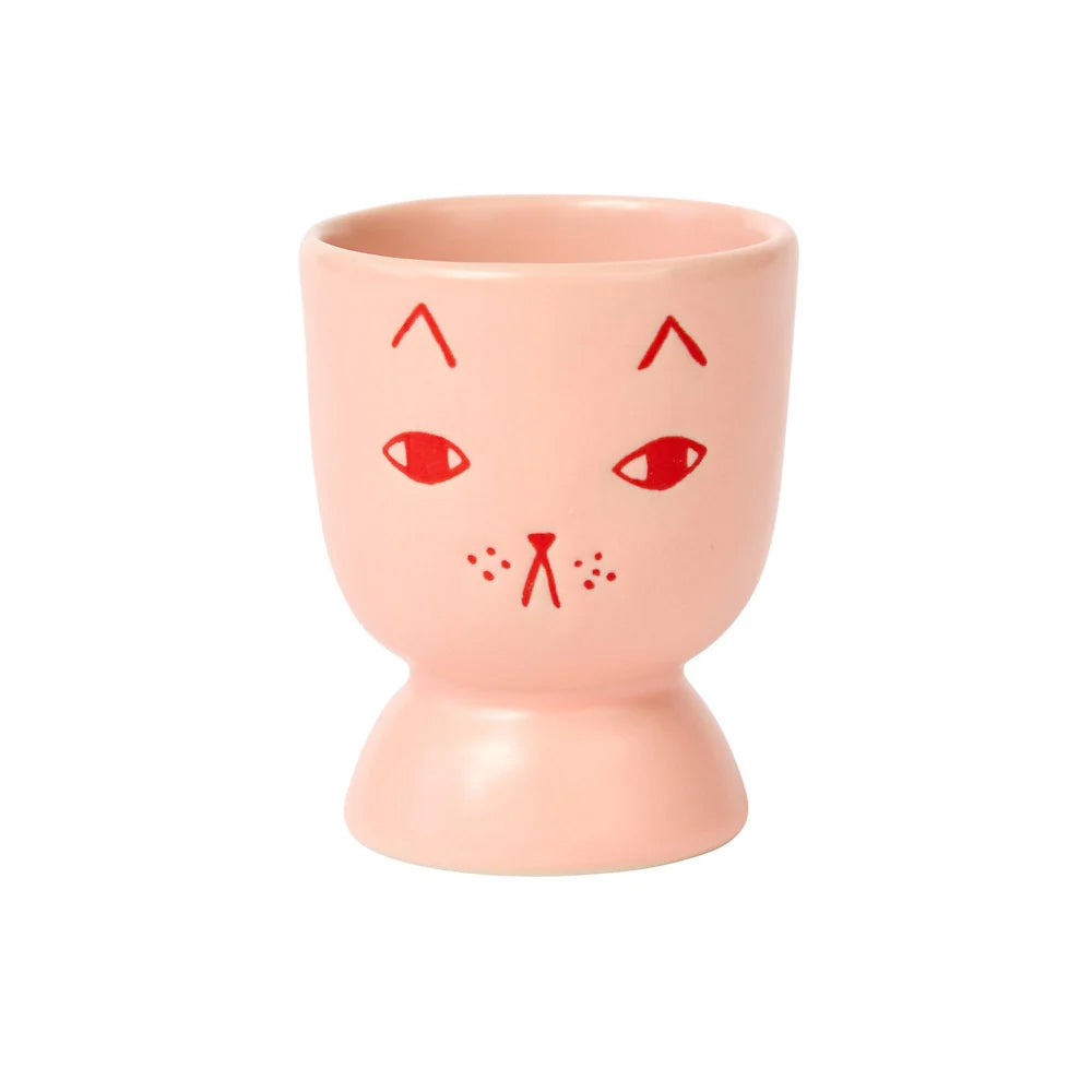 Pink ceramic cup with red cat face design on a white background