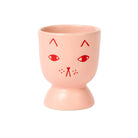 Pink ceramic cup with red cat face design on a white background